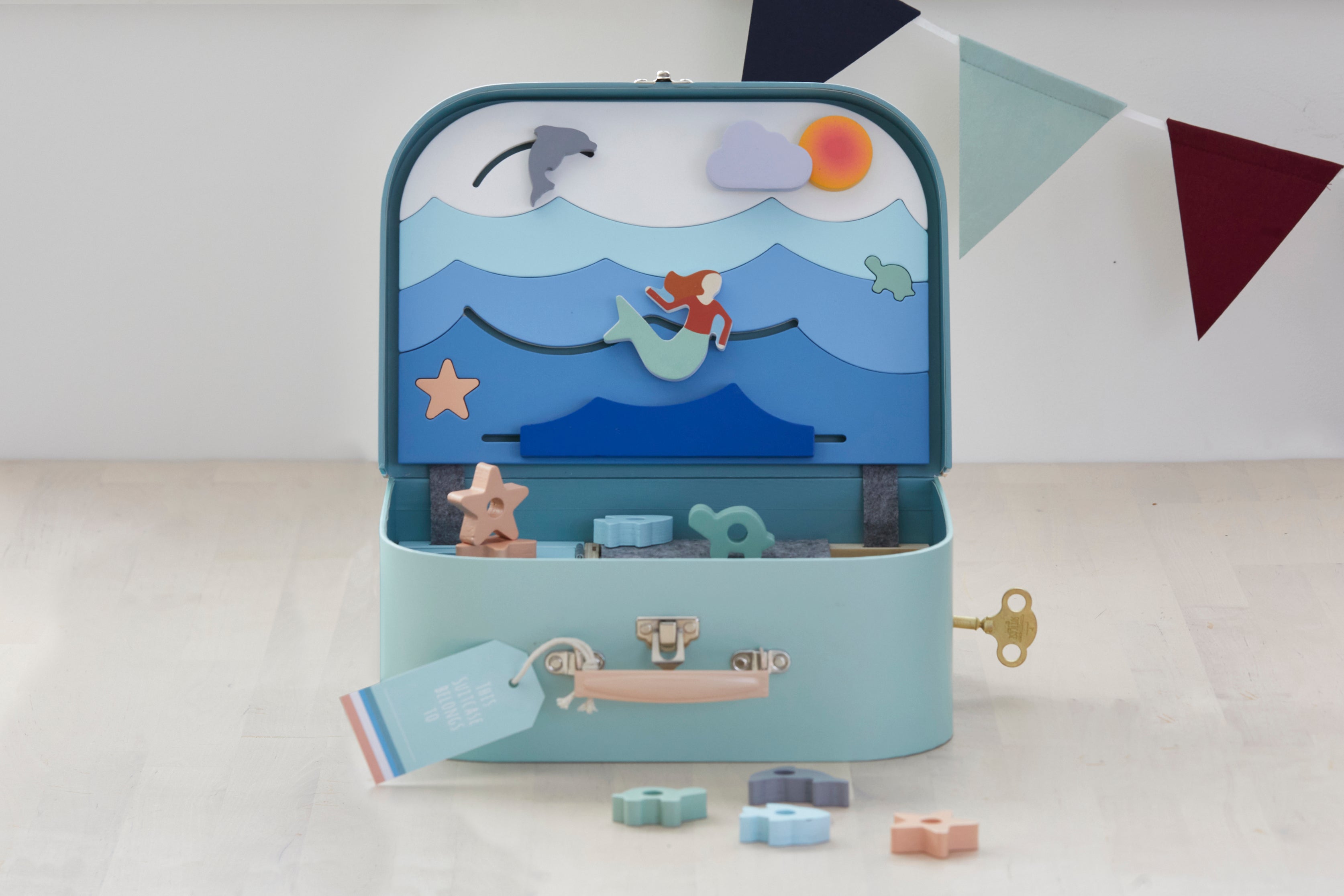 Load video: Children&#39;s educational ocean lover toy suitcase. Includes 1 treasure key, 16 wooden sea shapes, stickers and name tag for customising. Materials: sustainable &amp; recycled materials (FSC timber, recycled felt, cardboard). Original, educational and ethically produced. Supporting cognitive, fine motor, problem solving skills &amp; imaginative play. Easy to pack and carry around. Suitable for children age 3+ years.  Designed and prototyped in Australia. Environmentally friendly packaging.